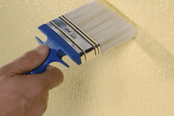 Hand streicht Wand gelb